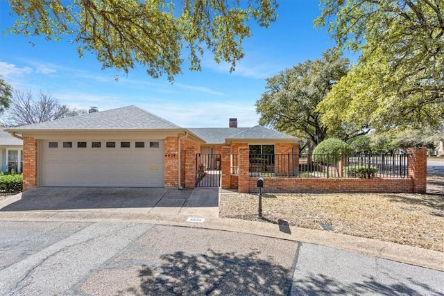 ranch-style home featuring driveway, a garage, brick siding, and a fenced front yard