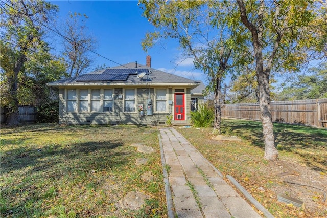 view of front of property with a front yard and solar panels