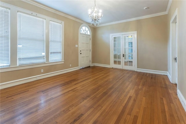 foyer featuring french doors, an inviting chandelier, wood-type flooring, and ornamental molding