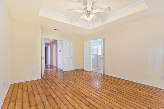 empty room featuring hardwood / wood-style floors, a raised ceiling, and crown molding