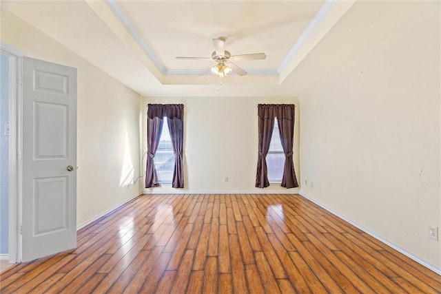 empty room featuring hardwood / wood-style floors, a raised ceiling, and ceiling fan