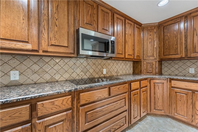 kitchen featuring backsplash, dark stone counters, and black stovetop