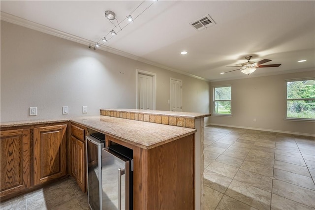 kitchen featuring kitchen peninsula, ceiling fan, and crown molding