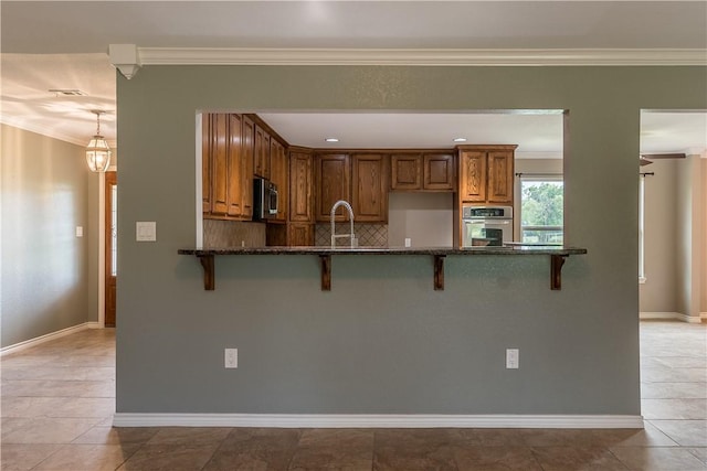 kitchen with a breakfast bar, ornamental molding, stainless steel appliances, and light tile patterned floors