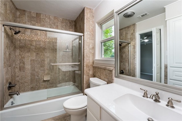 full bathroom with combined bath / shower with glass door, vanity, a textured ceiling, and toilet