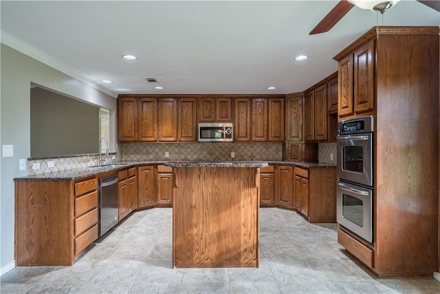 kitchen featuring a center island, backsplash, sink, dark stone countertops, and stainless steel appliances