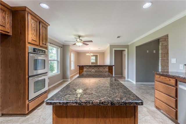 kitchen with a kitchen island, crown molding, stainless steel appliances, and dark stone counters