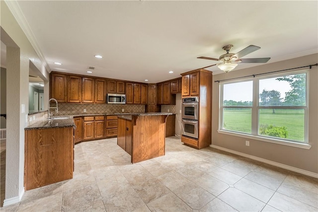 kitchen featuring sink, stainless steel appliances, backsplash, dark stone counters, and a breakfast bar area