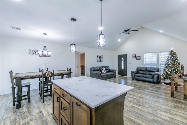 kitchen featuring ceiling fan, a kitchen island, decorative light fixtures, and light wood-type flooring