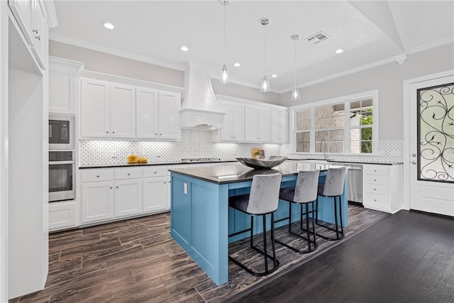 kitchen with a center island, custom range hood, appliances with stainless steel finishes, dark hardwood / wood-style flooring, and white cabinetry