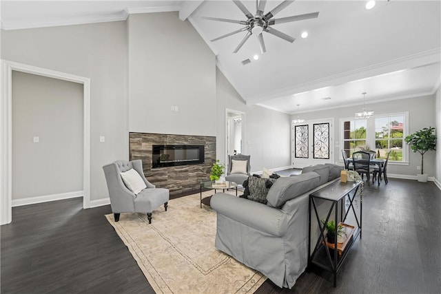 living room with dark hardwood / wood-style flooring, ornamental molding, ceiling fan with notable chandelier, beamed ceiling, and a stone fireplace