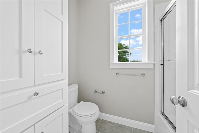 bathroom with tile patterned floors, toilet, and bath / shower combo with glass door