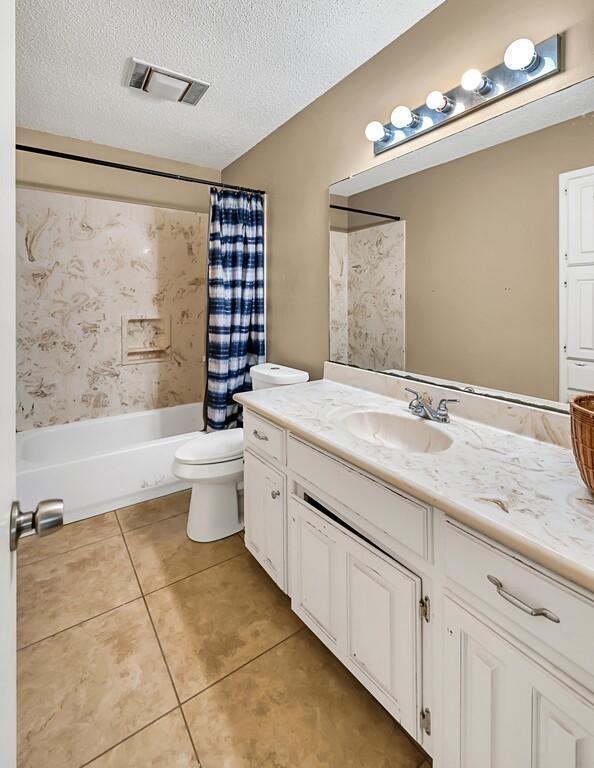 full bathroom featuring tile patterned floors, shower / bath combo, a textured ceiling, and toilet