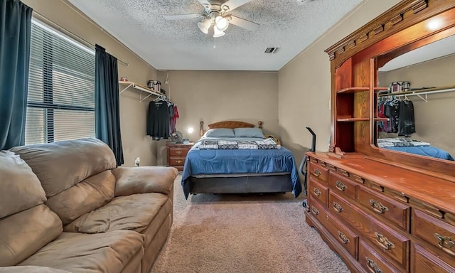 bedroom featuring a textured ceiling, ceiling fan, light carpet, and a closet