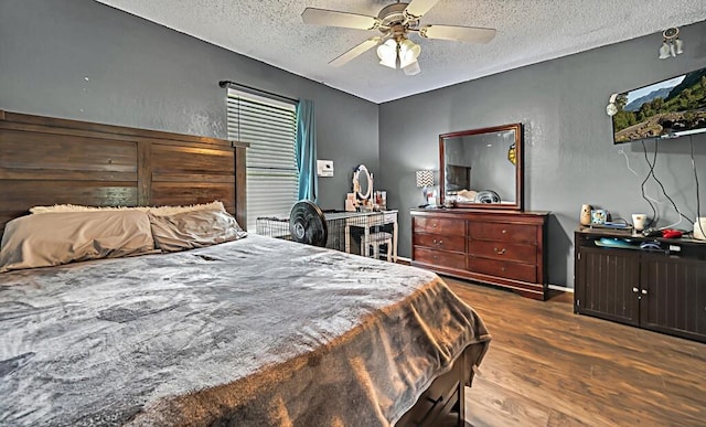 bedroom with a textured ceiling, ceiling fan, and dark wood-type flooring