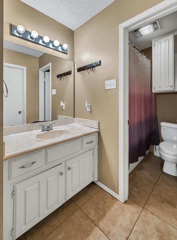 bathroom featuring tile patterned floors, vanity, toilet, and a textured ceiling