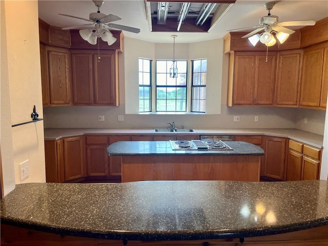 kitchen with stainless steel gas stovetop, a center island, ceiling fan with notable chandelier, and sink