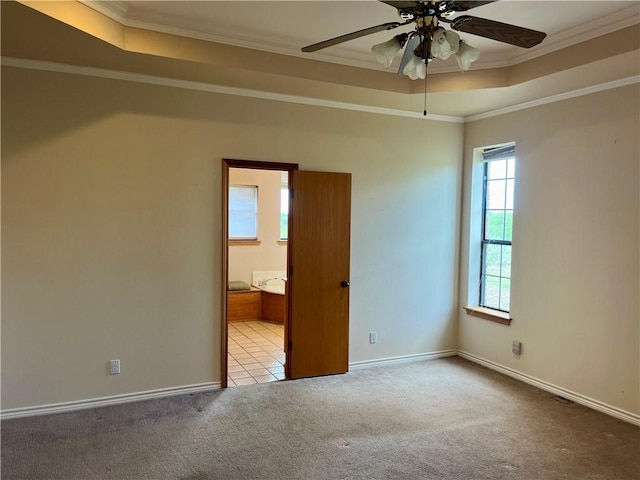 carpeted spare room featuring ceiling fan, crown molding, and a tray ceiling