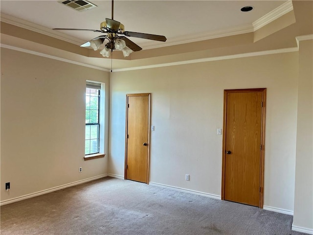 empty room with carpet, ceiling fan, a raised ceiling, and ornamental molding