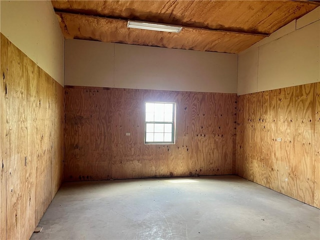 empty room featuring wood walls, concrete flooring, and wood ceiling