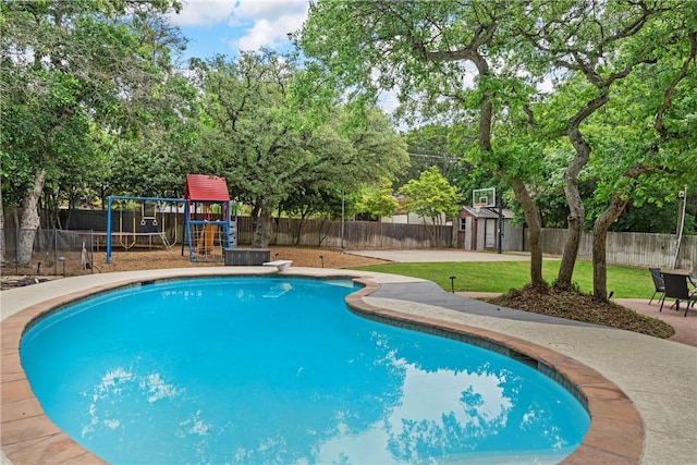 view of pool featuring a yard, a playground, an outdoor structure, and a fenced backyard