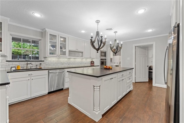 kitchen featuring a kitchen island, a sink, white cabinetry, appliances with stainless steel finishes, and dark countertops