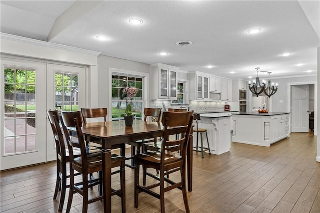 dining room featuring a chandelier, visible vents, ornamental molding, and wood finished floors