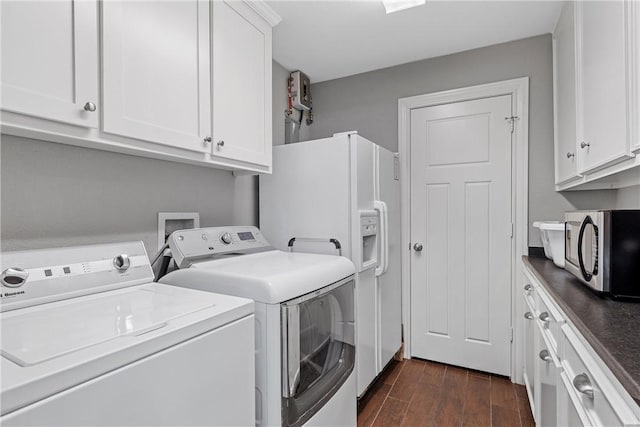 clothes washing area with separate washer and dryer, dark wood-style flooring, and cabinet space