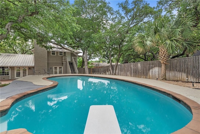 view of pool with a fenced in pool, french doors, stairway, a fenced backyard, and a diving board