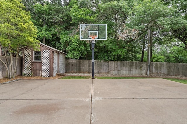 view of sport court with a shed, a fenced backyard, and basketball court