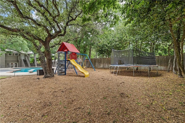 community playground with a trampoline, a fenced in pool, a fenced backyard, and stairway