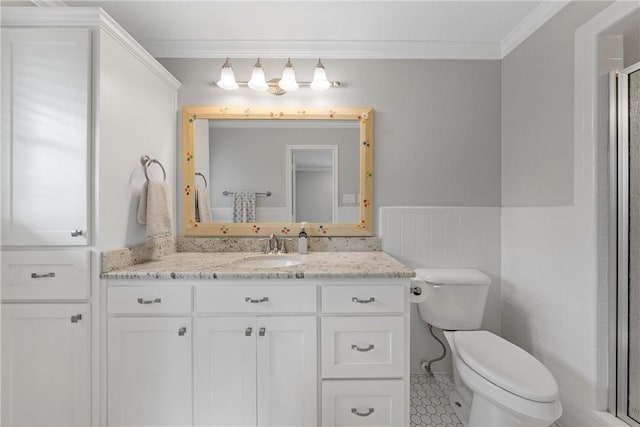 bathroom featuring toilet, a shower with door, crown molding, vanity, and tile walls