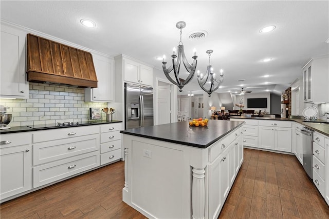 kitchen with dark countertops, premium range hood, stainless steel appliances, and ceiling fan with notable chandelier