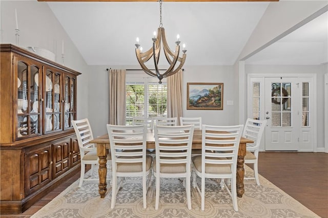 dining space with lofted ceiling, an inviting chandelier, and wood finished floors