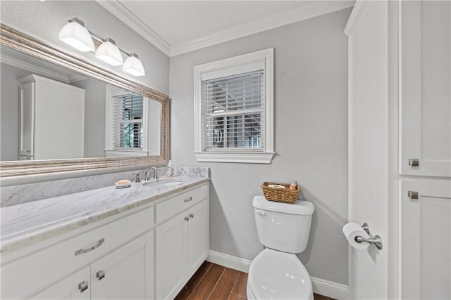 bathroom with toilet, ornamental molding, vanity, wood finished floors, and baseboards