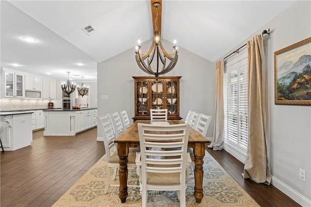 dining area featuring vaulted ceiling with beams, visible vents, an inviting chandelier, dark wood-type flooring, and baseboards