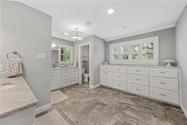 bathroom featuring toilet, baseboards, and two vanities