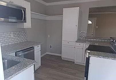 kitchen featuring white cabinetry, light stone counters, wood-type flooring, electric stove, and decorative backsplash