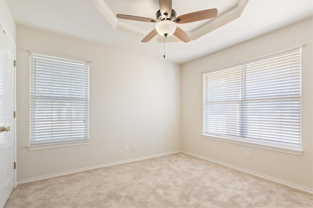 spare room featuring a ceiling fan, a tray ceiling, and light colored carpet