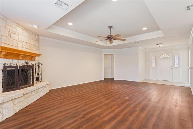 unfurnished living room featuring a fireplace, visible vents, a raised ceiling, and dark wood-style flooring