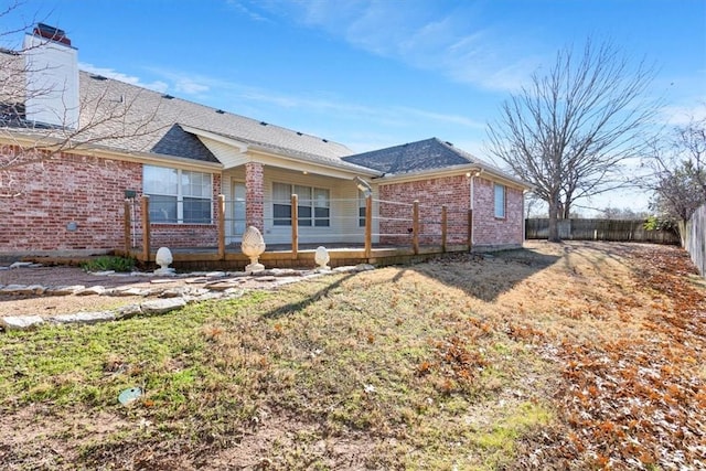 ranch-style house with brick siding, fence, roof with shingles, a chimney, and a front yard