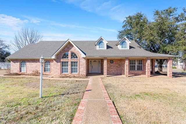 view of front of home featuring brick siding, a shingled roof, and a front yard