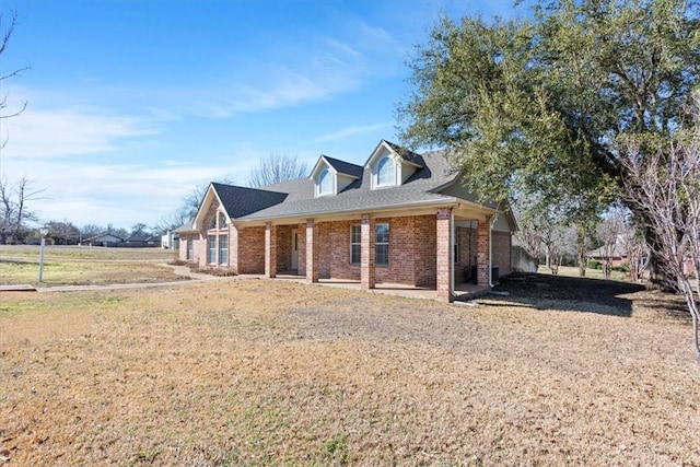 view of front of house featuring roof with shingles, brick siding, and a front lawn