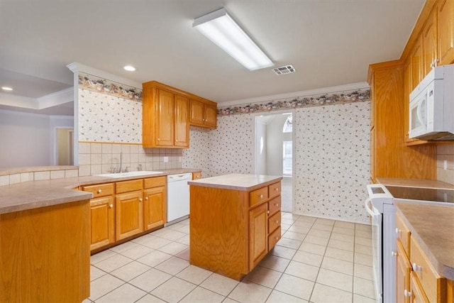 kitchen with white appliances, a sink, visible vents, light countertops, and a center island