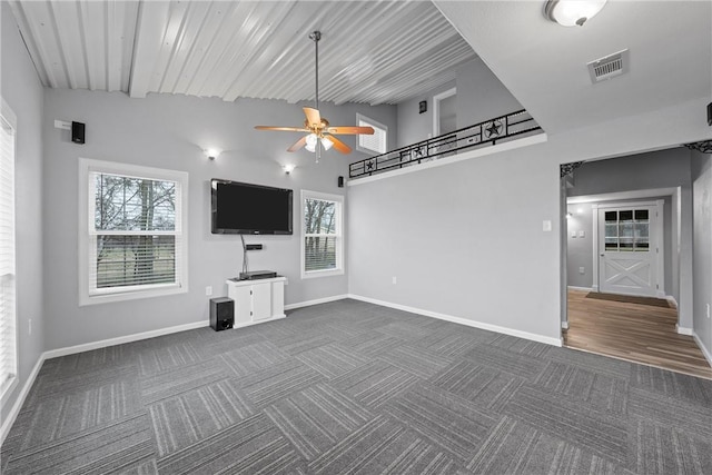 unfurnished living room with visible vents, dark carpet, baseboards, and ceiling fan