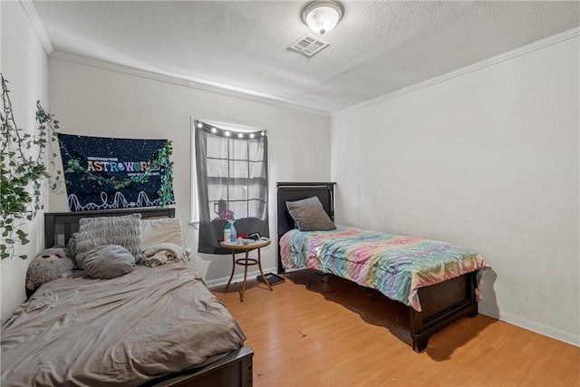 bedroom featuring crown molding, a textured ceiling, and hardwood / wood-style flooring