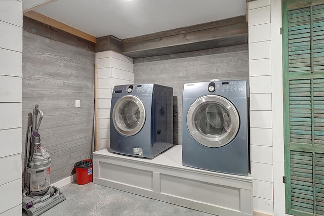 washroom featuring washing machine and dryer and wooden walls