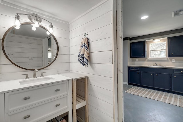 bathroom with concrete flooring, vanity, and wooden walls