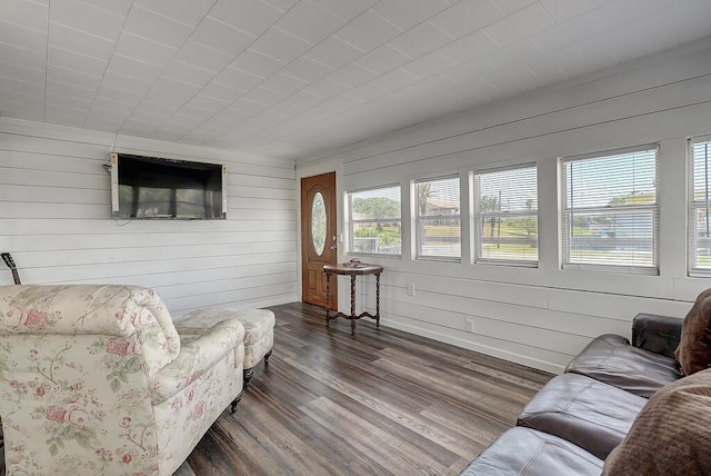 living room featuring dark hardwood / wood-style flooring and wooden walls