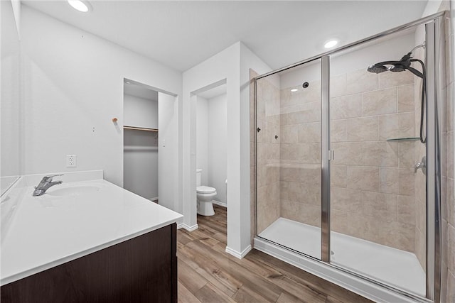 bathroom with hardwood / wood-style flooring, vanity, toilet, and a shower with door